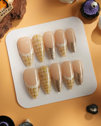 Tweed Light nail close-up with soft nude polish, yellow plaid art, and gold glitter tips
