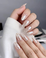 Close-up of Lemon soda press-on nails with pearly nude shimmer and milky white polka dots