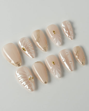 Venus short stiletto nails with pearly nude shine, shells, and gold details