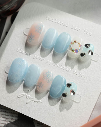 Winter wonderland press-on nails in extra short oval shape — Icy Blue Snowflakes, Rhinestone Wreath & Hearts.