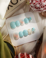 Winter wonderland press-on nails in extra short squoval shape — Icy Blue Snowflakes, Rhinestone Wreath & Hearts.