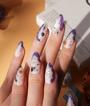 Witching Hour press on nails with a black spider web, bats, ghost, black cat and jack-o'-lanterns on a nude base with purple glitter edges - image 1