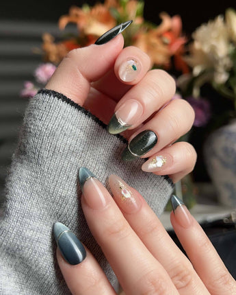 Close-up of Woodland Sea nails with dark green shimmer, gold French line, and shell glitters