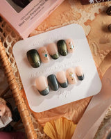 Woodland Sea nail set with deep green cat-eye tips, gold linework, and shell glitter accents