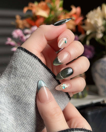 Woodland Sea press-on nails with dark green cat-eye shimmer, gold French lines, and shell glitter