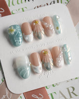 Yasawa Blue glossy vacation nails with translucent blue tones and sculpted shell details