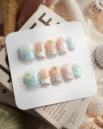 Yasawa Blue extra short coffin nails with jelly blue shell swirls and pearl accents