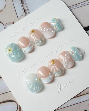 Yasawa Blue extra short squoval nails with 3D shells, pearls, and jelly blue glow