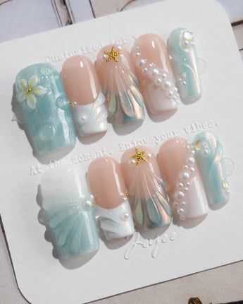 Yasawa Blue medium square nails with ocean-blue swirls, pearls, and 3D shell accents