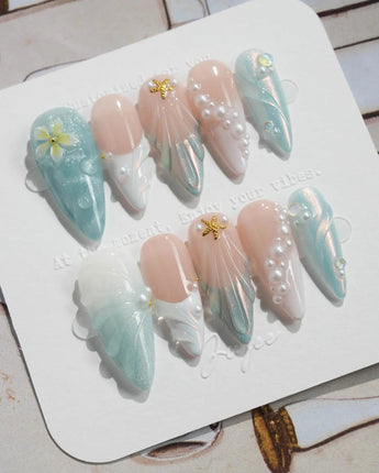 Yasawa Blue medium stiletto nails with pearly blue-white shells and starfish accents